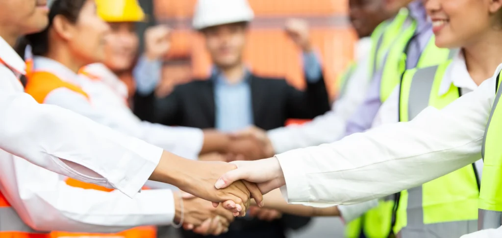 Fotografía de colaboradores de una nave industrial estrechando sus manos que representa que es el cumplimiento laboral.