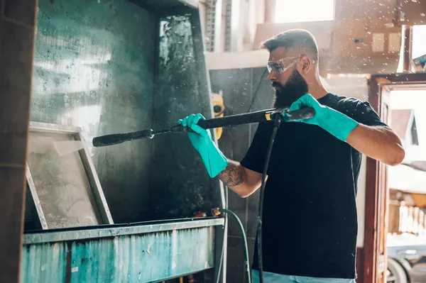 Fotografía de un hombre utilizando lentes de seguridad mientras realiza su trabajo como operario de limpieza.