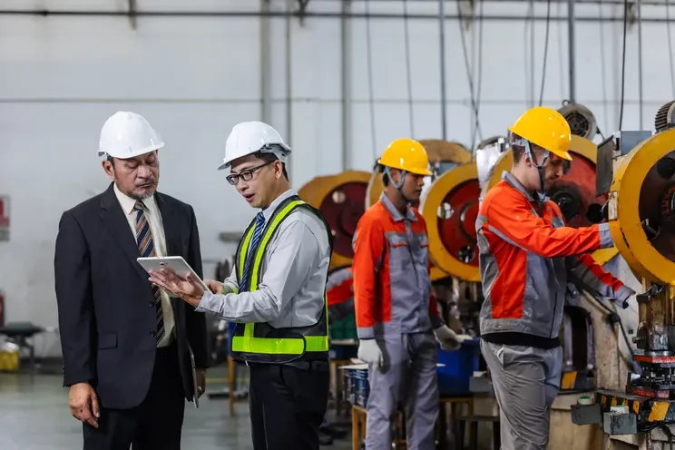 Cómo construir un calendario de mantenimiento preventivo sin afectar la producción: 2 hombres con casco blanco conversando.